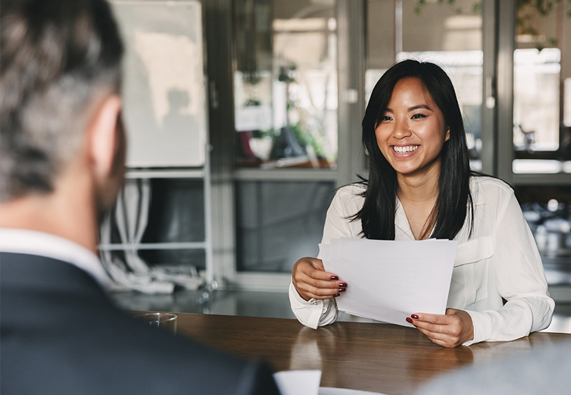 A person interested in a career at Landmark, holds their resume and smiles across the desk during an interview.