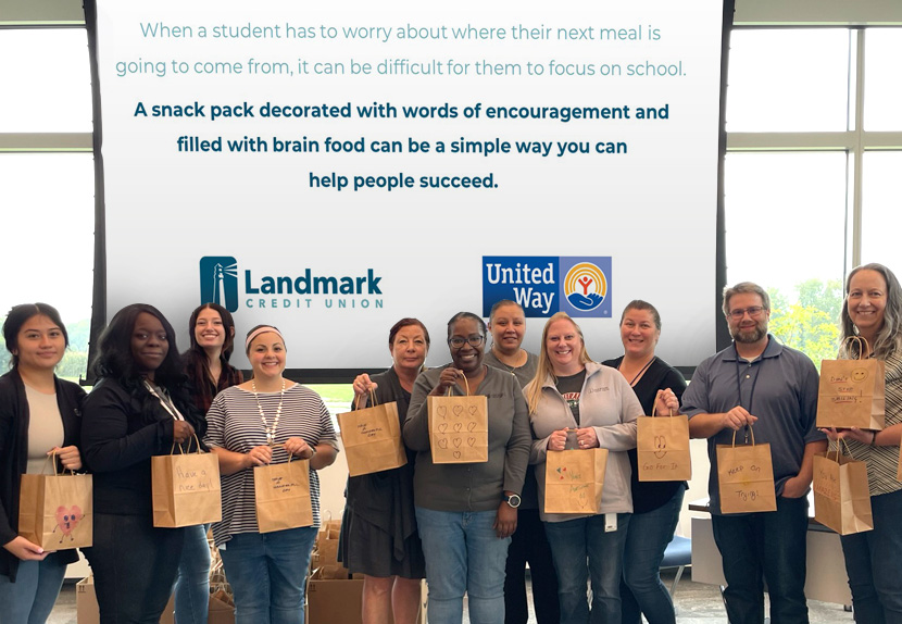 A group Landmark associates smile and hold lunch bags that they packed during a community volunteer event.