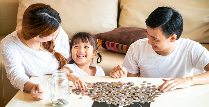 A couple is joined by their young daughter, who is learning about the importance of saving money from them.