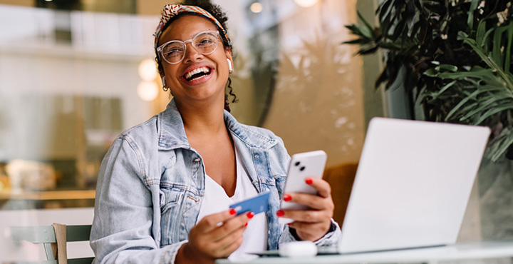 Person at computer with phone and credit card, planning savings goals.