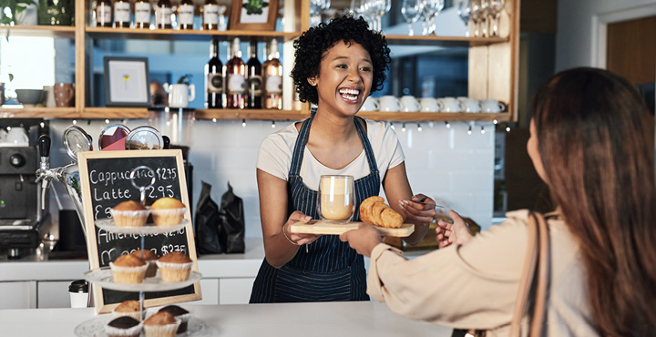 A smiling member is working the counter at a summer job in a bakery.