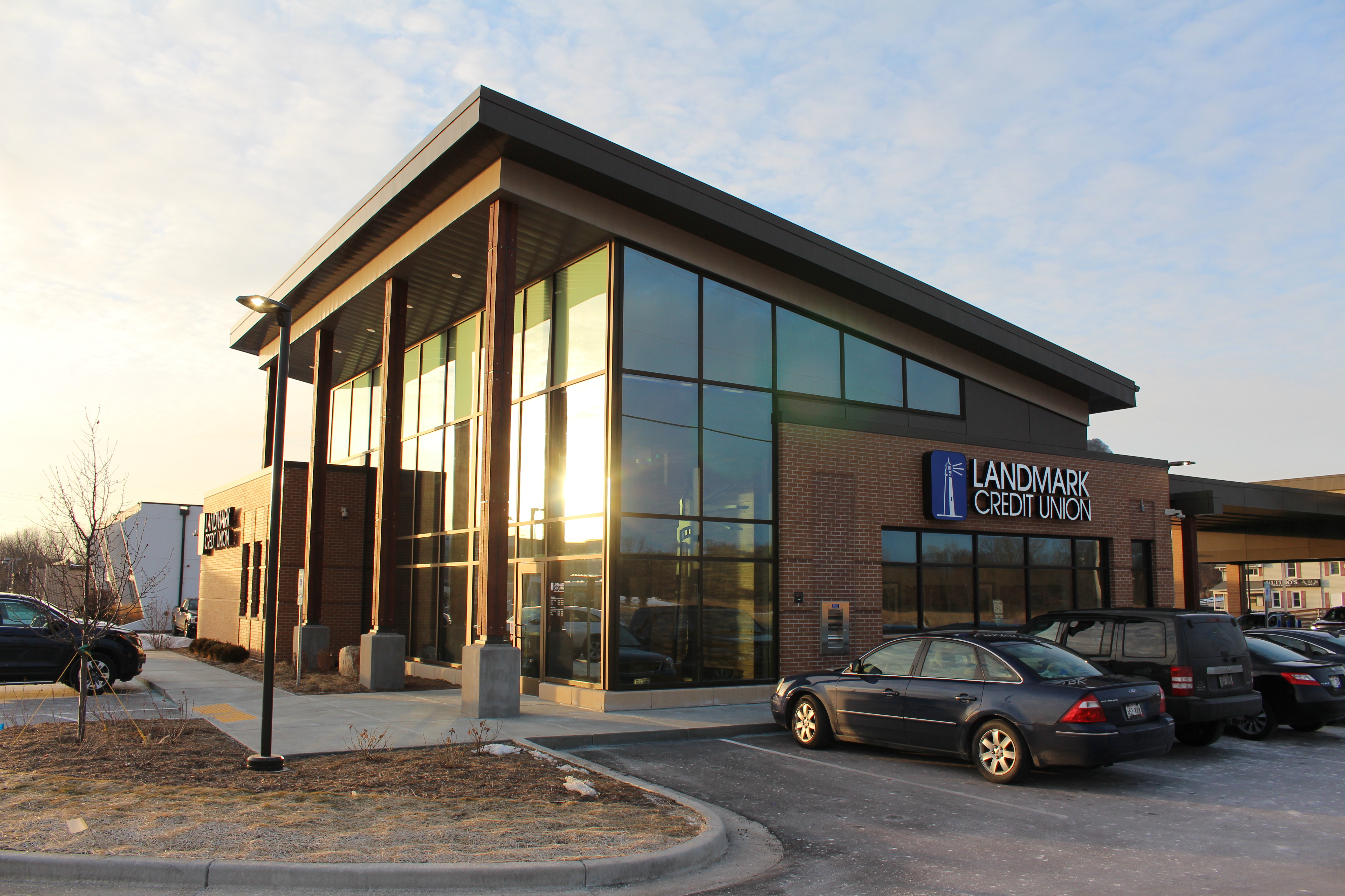 An exterior view of Landmark Brookfield West branch that is a large modern brick building with large glass doorway and windows.