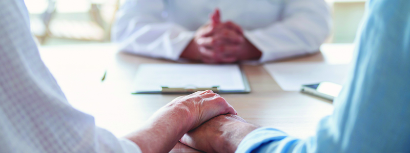 Couple holding hands talking to advisor