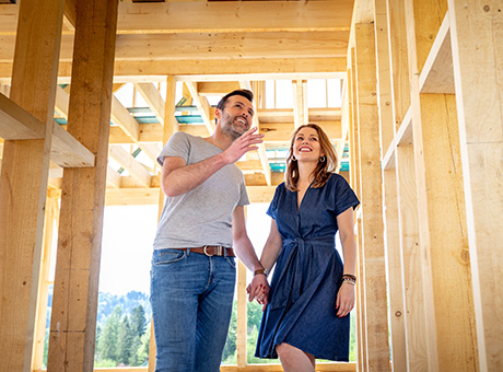 A loving husband and wife are holding hands at a construction site of their new dream home. 
