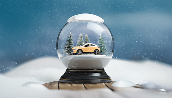 Snowglobe on a winter landscape featuring a car within the globe. 