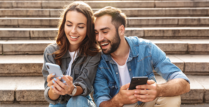 A young couple shares a smile as they explore using the Landmark Credit Union mobile app to manage their loans.