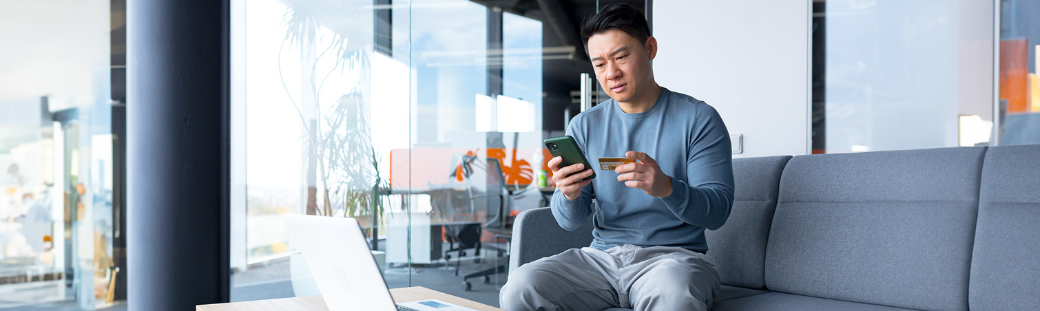 A member is at home, using their phone to prevent themselves against wire transfer scams.
