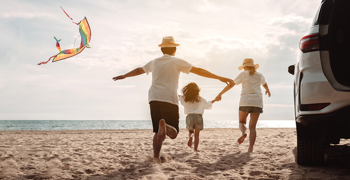 A happy family is enjoying their time flying a kite on the beach. 
