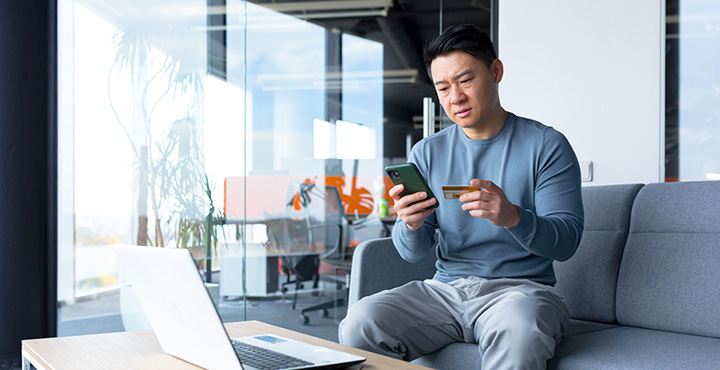 A member is at home, using their phone to prevent themselves against wire transfer scams.