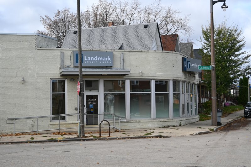 An exterior of Landmark Credit Union's Bay View branch depicting a white building with a glass doorway and Landmark's logo.