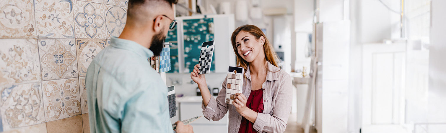 A youthful couple is examining bathroom tiles in a store.e.