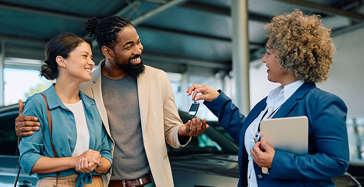 Couple receiving keys to their new car