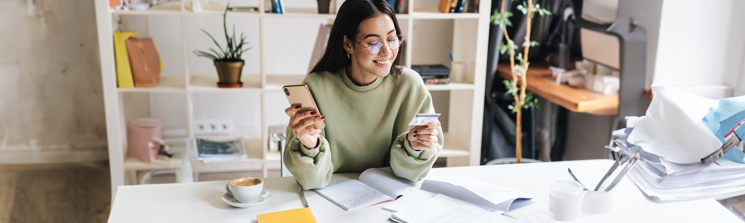 At home, a smiling member looks down at the credit card in their hands.