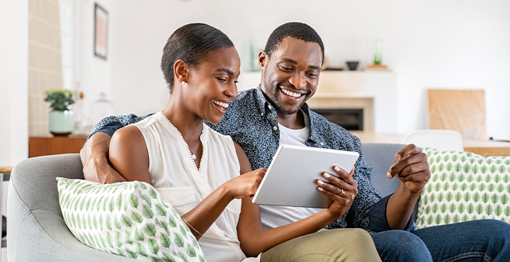 Couple sitting on couch looking at a tablet