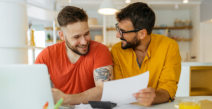 A couple sits at the table in their home as they look over guides on merging their accounts.