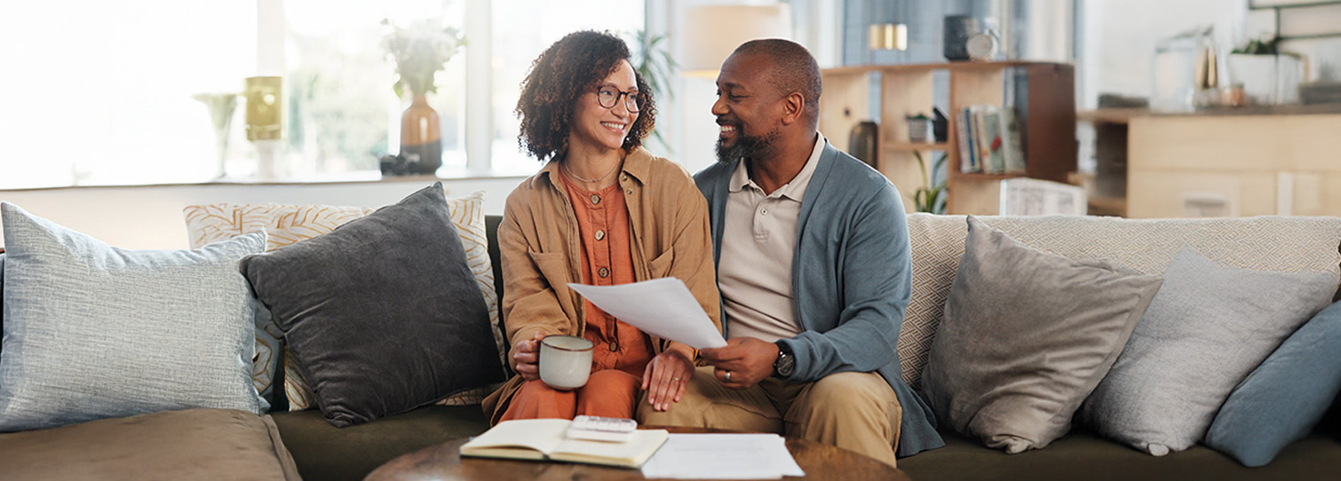 Couple sitting on couch looking through financial documents